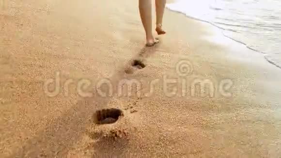 4k视频性感的女性双脚在夕阳下的沙滩和海浪上行走视频的预览图