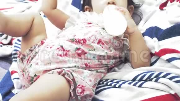 亚洲妈妈在家喂宝宝一瓶牛奶面带微笑幸福的亚洲家庭理念视频的预览图
