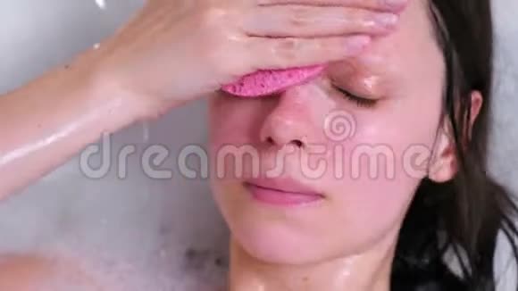 女人用一块海绵从浴室里的灌木丛中洗脸面的特写视频的预览图