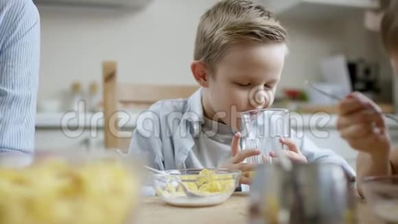 在午餐时间男孩用大玻璃杯喝橙汁视频的预览图