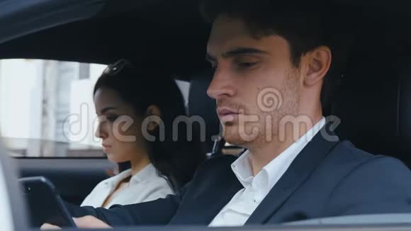 年轻英俊的男人坐在他的车轮边看着摄像机坐在车里的男人和女人视频的预览图