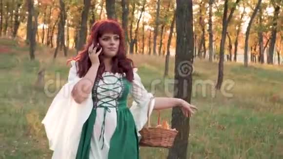 可爱迷人的大女孩在秋天的森林里有着火红的头发享受着朝阳和阳光的光芒视频的预览图