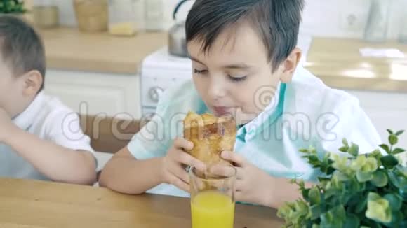 两个男孩在厨房里吃羊角面包视频的预览图