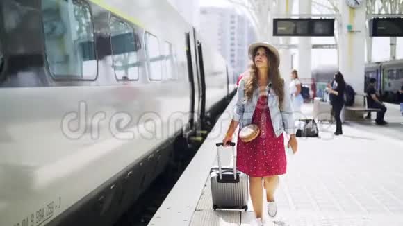 带着手提箱走在站台上的漂亮女人视频的预览图