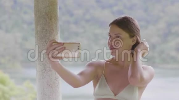 迷人的女人在绿山覆盖热带森林的手机上摆出自拍照片旅游妇女视频的预览图