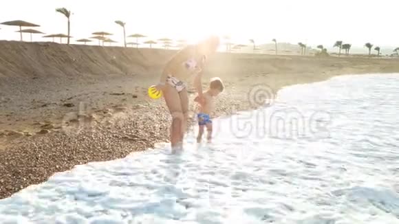 4k视频小男孩牵着妈妈的手在大海的沙滩上大浪漫步视频的预览图