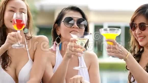 三个年轻的亚洲女人幸福地在沃尔游泳池喝饮料视频的预览图