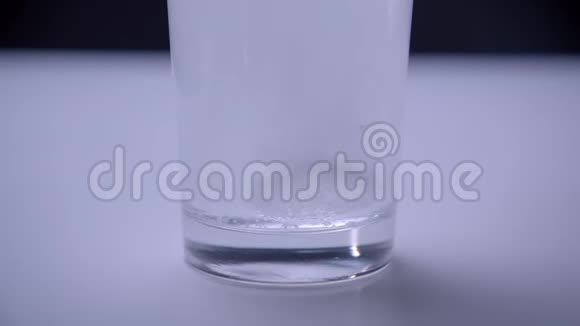 白色桌子上透明玻璃底部溶解药丸的特写镜头视频的预览图