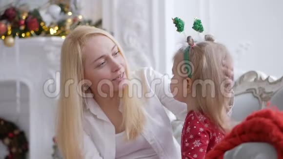 坐在壁炉边的沙发上装饰着圣诞节的装饰这位女士和她的小女儿在聊天中玩得很开心视频的预览图