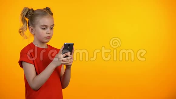 微笑的小女孩在智能手机上打字微笑的教育应用程序小玩意视频的预览图