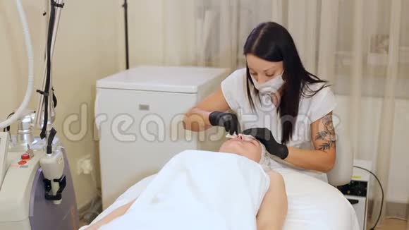 美容师在水疗中心用棉签擦拭一个年轻女孩的脸视频的预览图