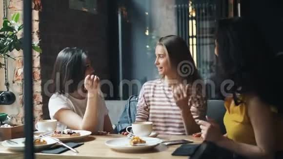 快乐的女性朋友在现代咖啡馆里说着然后做着击掌笑着视频的预览图
