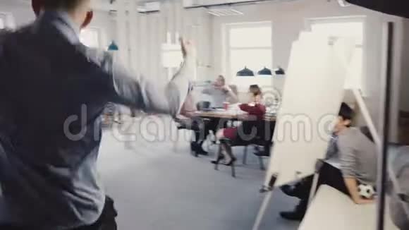 镜头跟随快乐商人走进办公室做滑稽的庆祝舞蹈多民族工人笑着鼓掌视频的预览图