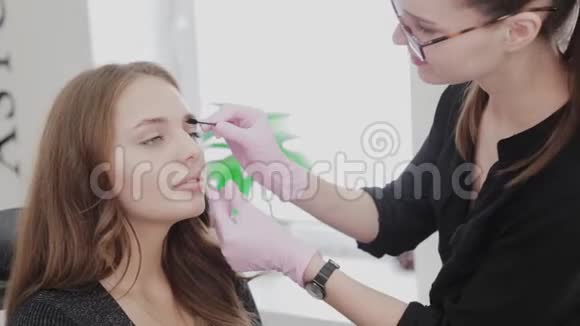 专业化妆师用一个漂亮女孩的特殊眉毛刷梳眉毛美女客户视频的预览图