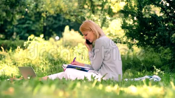 年轻的女学生坐在公园里学习美丽的花园春夏休闲活动视频的预览图