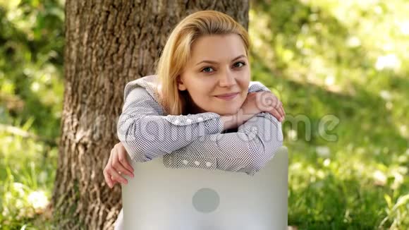 公园里一个拿着笔记本电脑的女学生的特写女孩真诚地微笑公园里兴奋的女孩视频的预览图