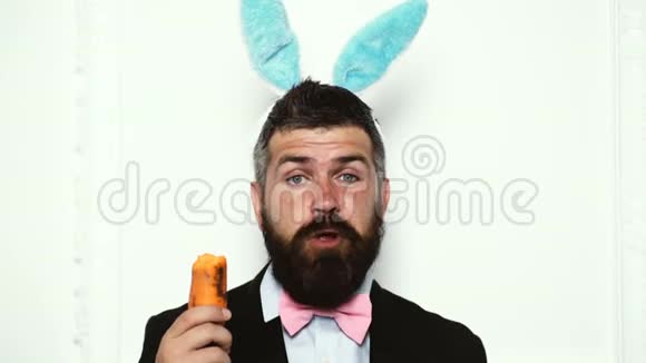 复活节兔子男孩被隔离在白色背景上兔子耳朵里长胡子的人在白色背景上吃胡萝卜复活节快乐视频的预览图