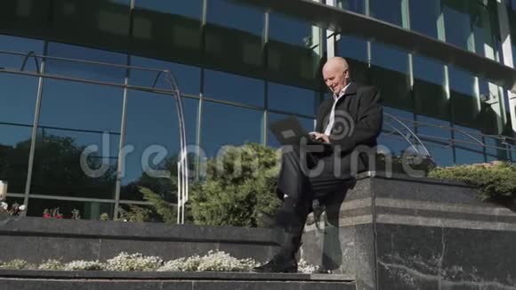 老人在城里用笔记本电脑工作视频的预览图