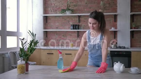 家务幸福的管家女孩戴着橡胶手套用清洁剂清洁灰尘家具视频的预览图