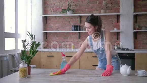 家庭惯例微笑的家庭主妇女孩戴着橡胶手套清洁脏家具与化学视频的预览图