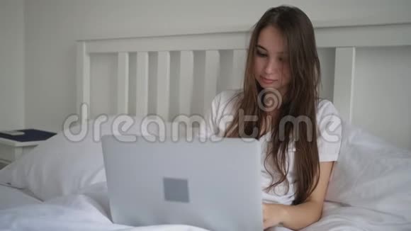 女人早上坐在床上写着笔记本视频的预览图
