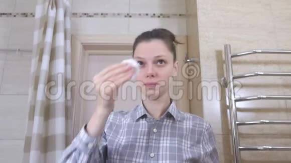 浴室里戴眼镜的睡女人用化妆棉擦脸视频的预览图