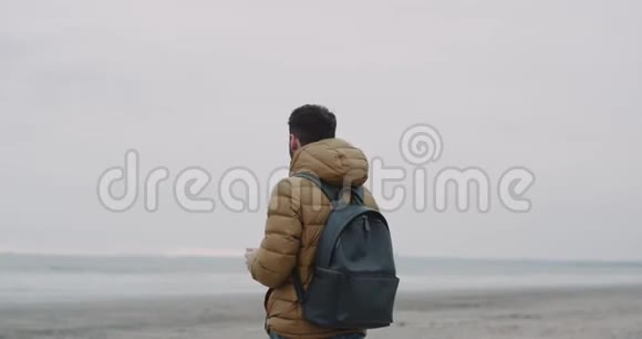 在海边拿着手机的帅哥的肖像男孩在看手机应用程序4k视频的预览图