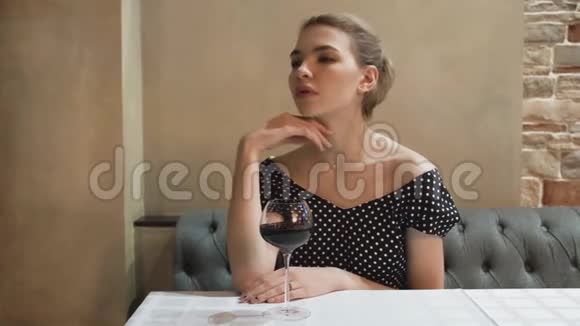 一位年轻女子穿着晚礼服在一家餐馆喝着一杯葡萄酒的肖像性感的手势和温柔的外表视频的预览图