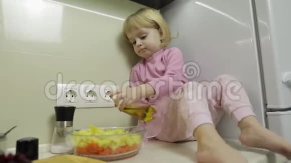 小女孩正坐在厨房里准备沙拉视频的预览图