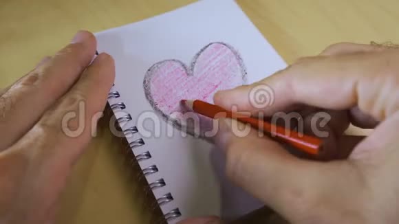 爱的心在笔记本上笔在橙色的木桌上视频的预览图
