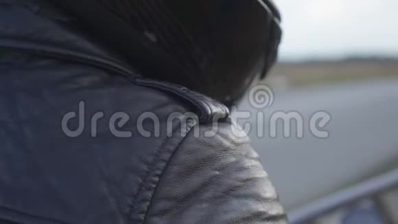 未识别的摩托车骑手黑色皮夹克和头盔坐在摩托车户外爱好旅游和视频的预览图