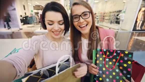 在购物中心自拍的年轻女学生的视角镜头展示了明亮的纸袋和拇指视频的预览图