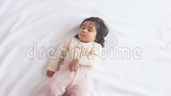 可爱可爱的非洲女婴躺在舒适的床上看着摄像机视频的预览图