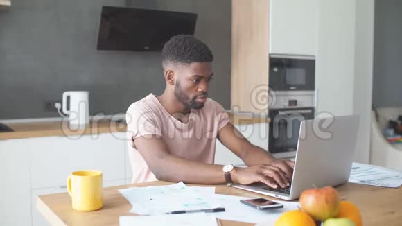 非洲男人用笔记本电脑而白种人女朋友孤独地站在厨房里视频的预览图
