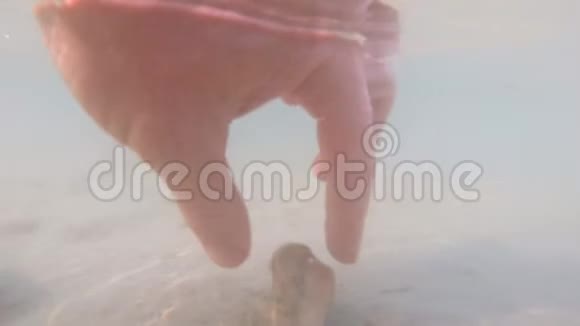 手拿石头在水下脚踩沙子多云的水视频的预览图