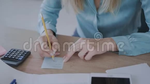 细节现代办公室女性手特写一个女孩依靠计算器并在笔记本4K做笔记视频的预览图