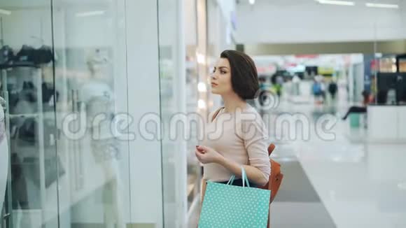 漂亮的女孩正在购物中心开会用纸袋展示购物讨论价格和服装视频的预览图