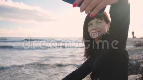 年轻的黑发女孩在海边的岩石海滩上自拍视频的预览图