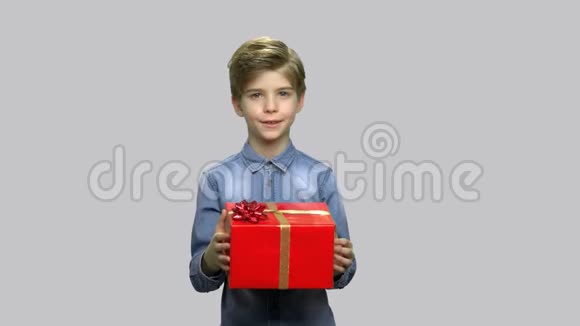 小男孩在灰色背景上送礼物盒视频的预览图