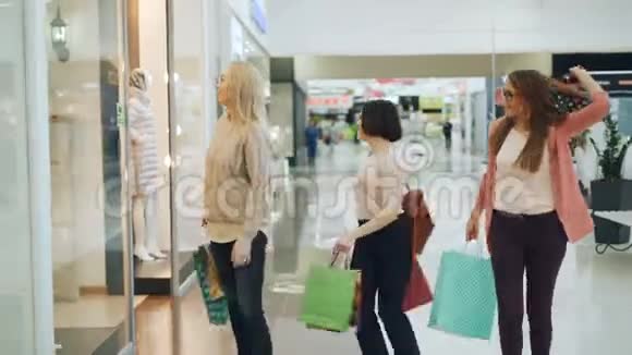 一群快乐的女孩在购物中心玩得很开心他们拿着纸袋走路笑着跳舞指着里面的商品视频的预览图