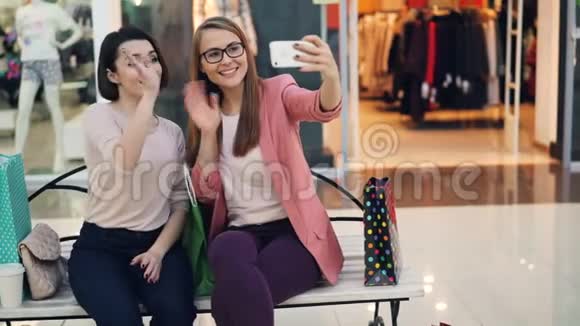 现代年轻女性正在使用智能手机从购物中心进行在线视频通话女孩们在聊天在笑视频的预览图