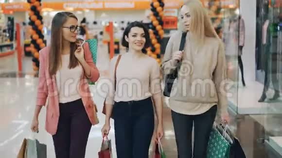 漂亮的年轻女人在购物中心散步时拿着纸袋购物零售快乐视频的预览图