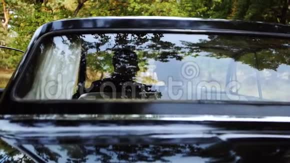 一对幸福的新婚夫妇开着一辆黑色老式车微笑亲吻视频的预览图