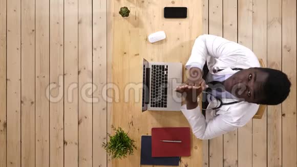 年轻的非洲男性医生打字抬头看相机说话视频的预览图