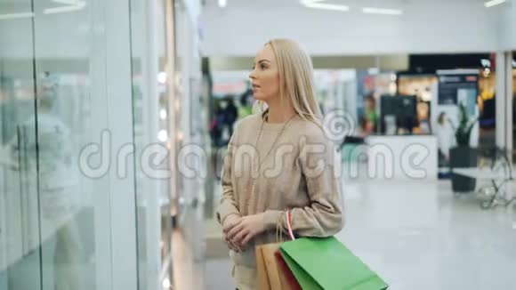 快乐的年轻女性朋友们在购物中心开会讨论购买商品然后用纸袋看商品视频的预览图