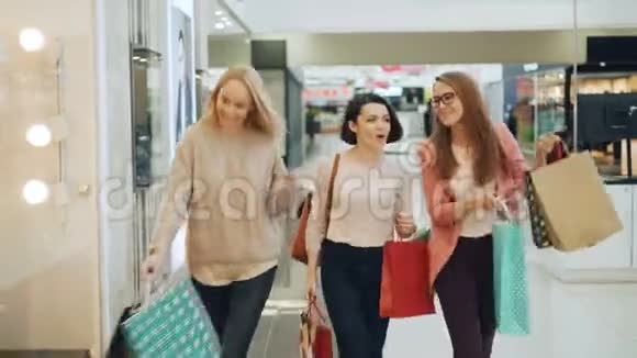 漂亮的女朋友在商场里玩得很开心他们用纸袋跳舞转过身笑着笑着视频的预览图
