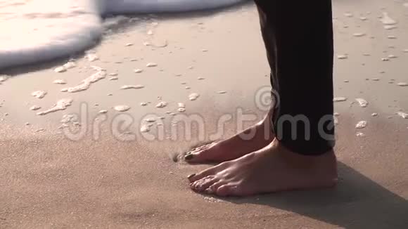 女人脚在湿沙上留下痕迹波浪用泡沫冲走夏季海洋视频的预览图
