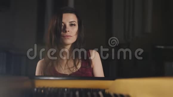 穿紫色衣服的女人在黑暗的音乐厅里弹钢琴视频的预览图