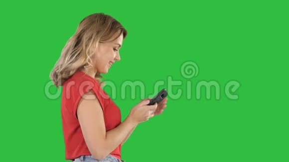 快乐可爱的美女玩游戏用手机放在绿色的屏幕上铬键视频的预览图