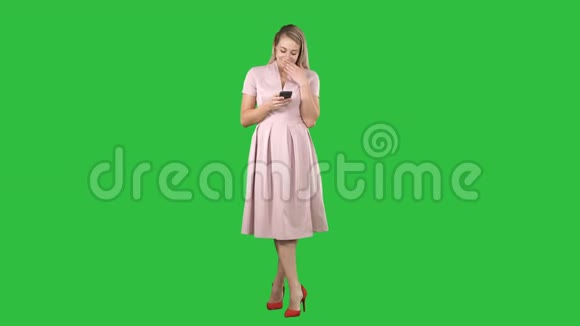 一个穿着夏天衣服的漂亮微笑的女孩用手机的肖像绿色屏幕上的短信色度键视频的预览图